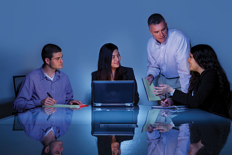 Psychology students and a professor evaluate data from a project.